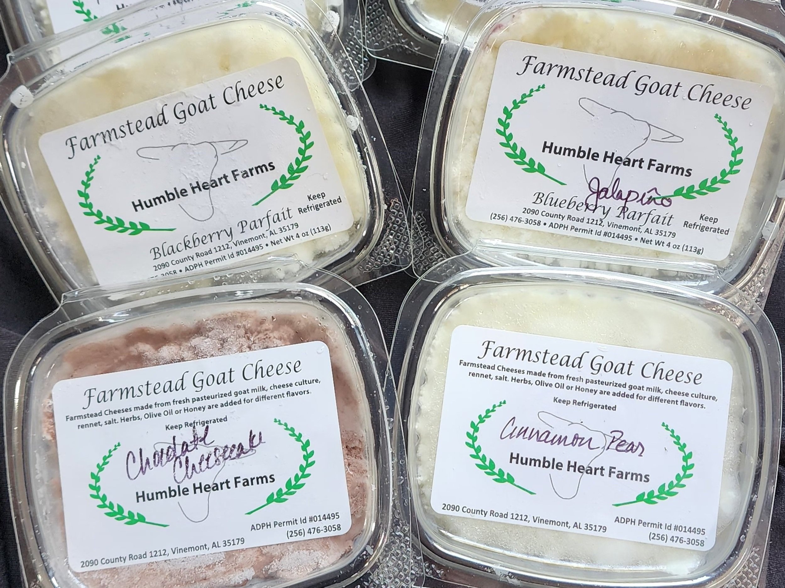 Farmstead goat cheese varieties from Humble Heart Farms, including Blackberry Parfait, Blueberry Parfait, Chocolate Cheesecake, and Cinnamon Pear, displayed in clear containers with labels.